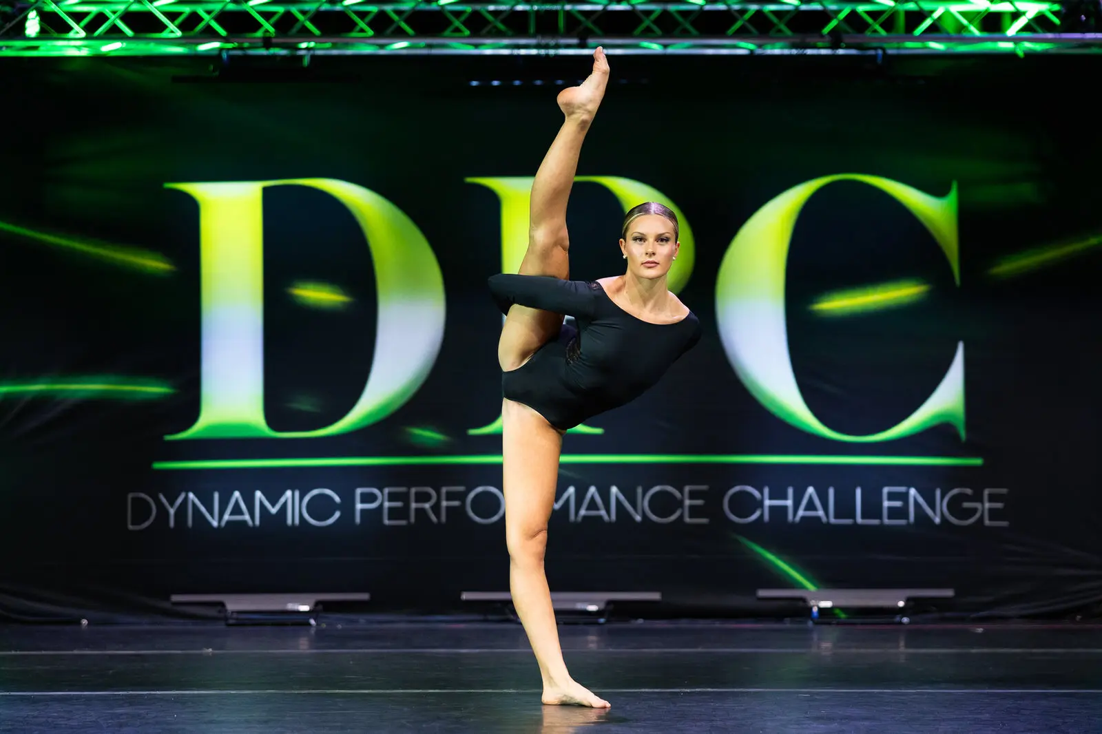 A dancer in an arabesque in front of the glowing DPC backdrop