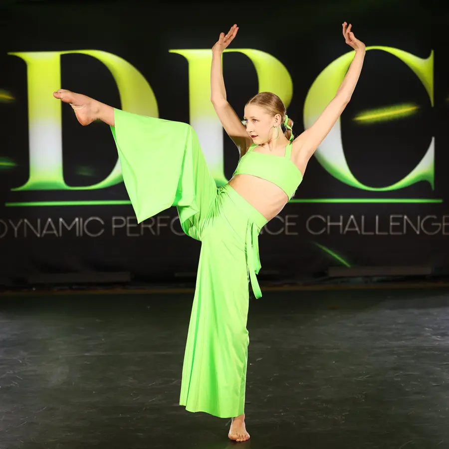 A competition dancer in a bright green costume on the DPC stage